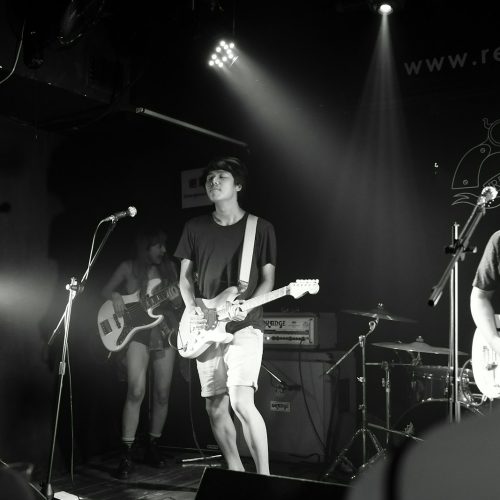 man in white shirt playing guitar on stage